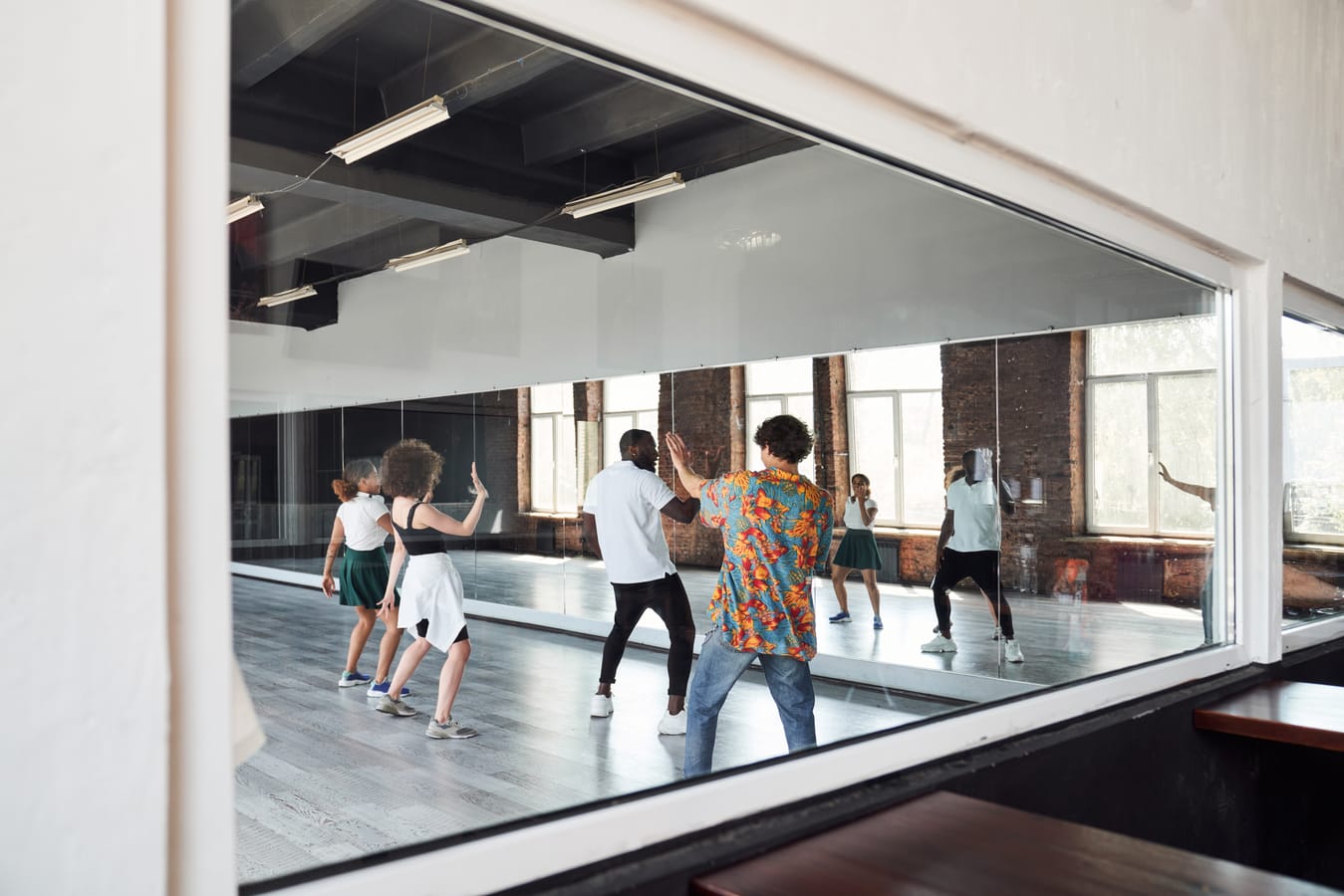 Dance team rehearsing together in front of full-wall studio mirrors