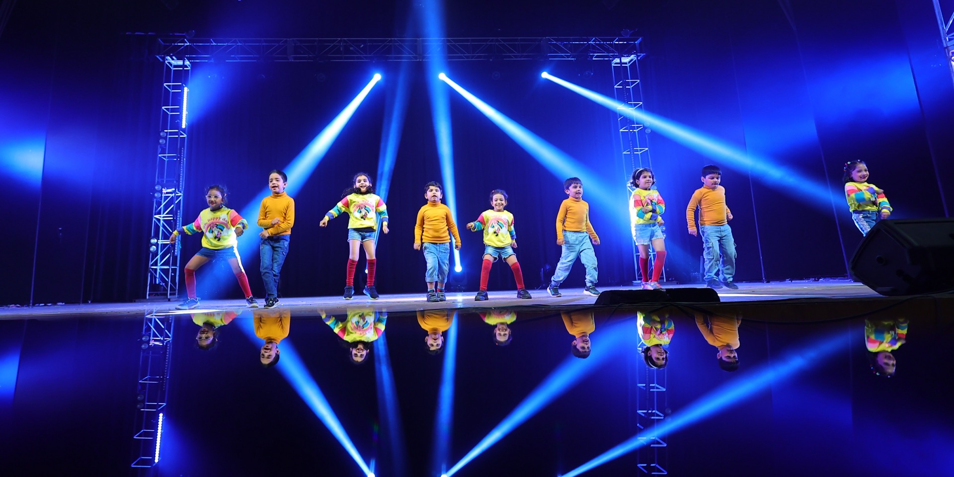 Junior batch lineup under blue stage spotlights at Twist N Turns Dancing Wonder