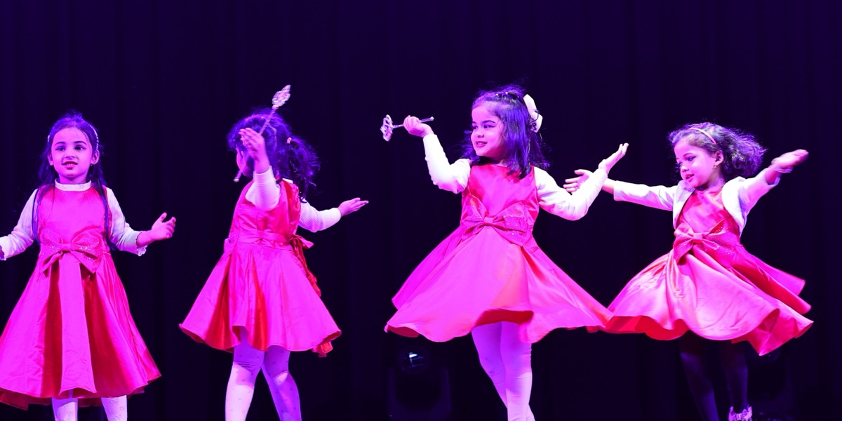 Toddler dancers in pink dresses performing on stage at Dancing Wonder